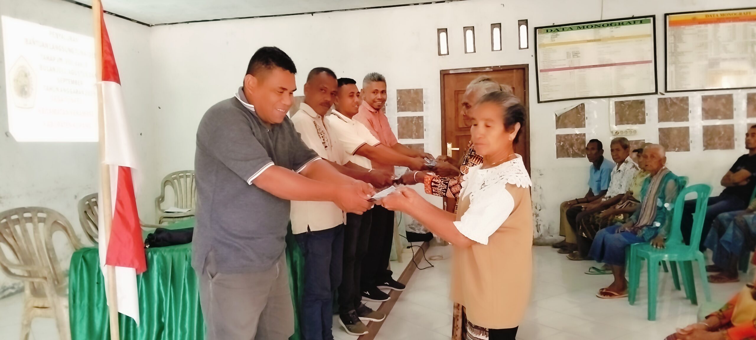 Ket. Foto: Penyerahan Bantuan Langsung Tunai (BLT) Dana Desa (DD) secara Simbolis oleh Kepala Desa, Ketua BPD, dan Perangkat Desa Kepada Masyarakat Penerima Manfaat.